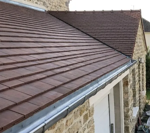 Couverture neuve en tuiles plates et gouttière en zinc sur une maison en meulière à Saint-Maur-des-Fossés